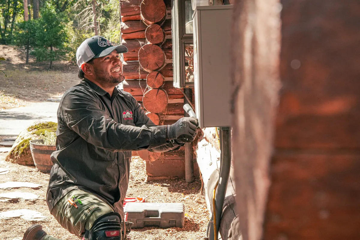 Apex technician running the gas fuel line to a standby generator at a log home