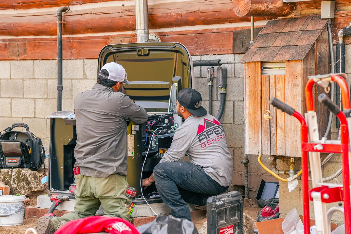 Apex technician servicing an open standby generator enclosure on a deck