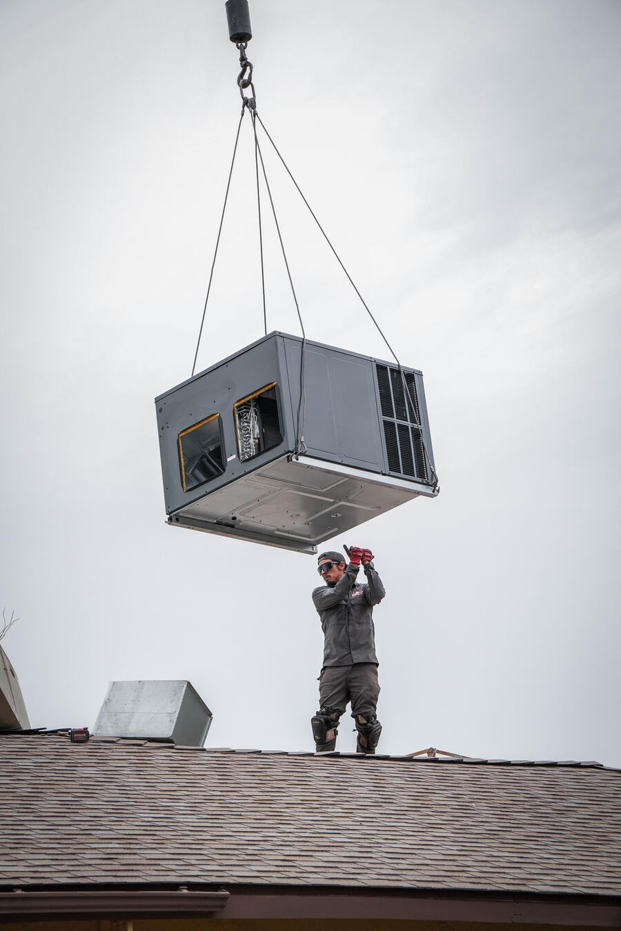 Apex crew guiding a crane-lifted HVAC unit into place