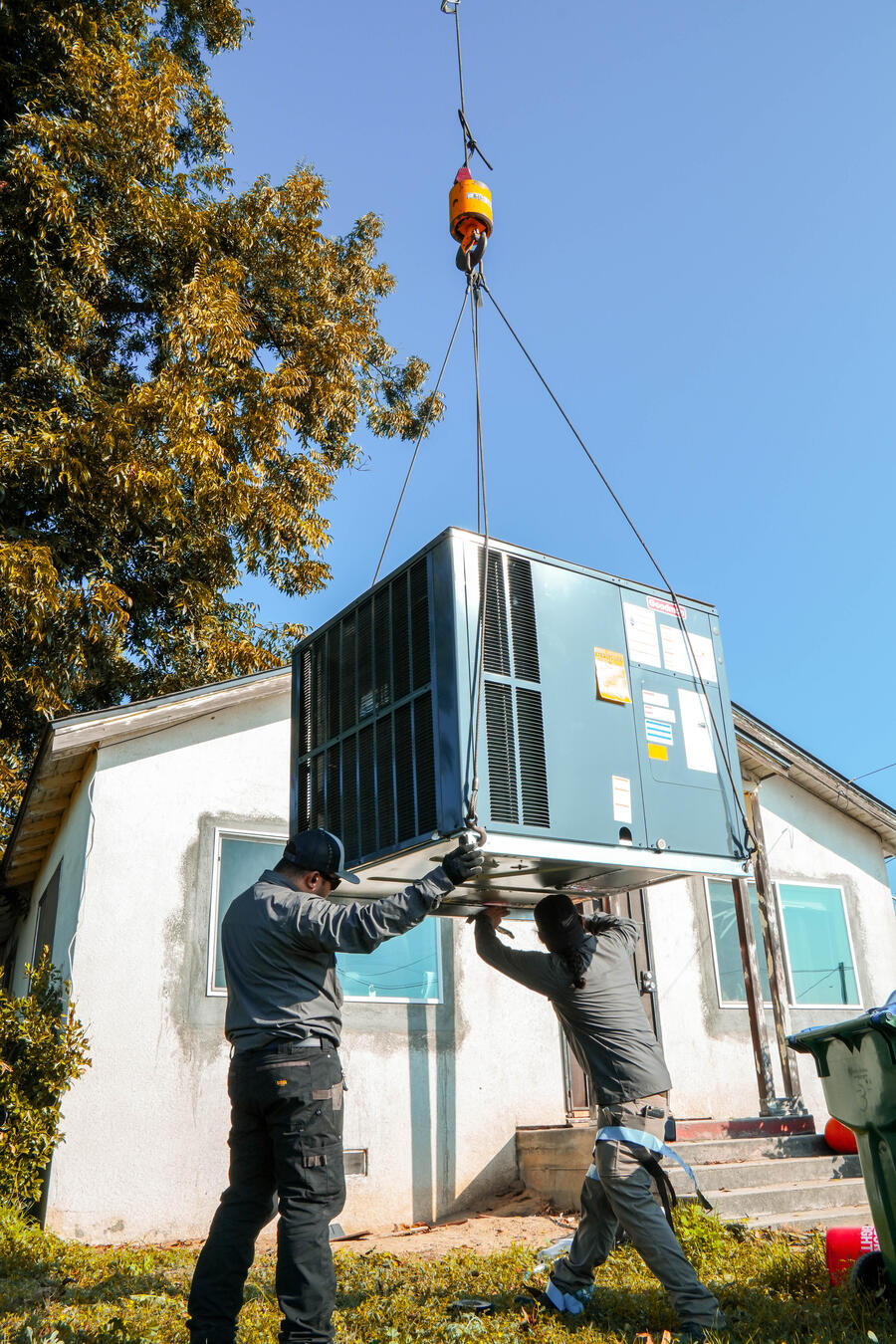 Two Apex technicians working under a suspended HVAC unit