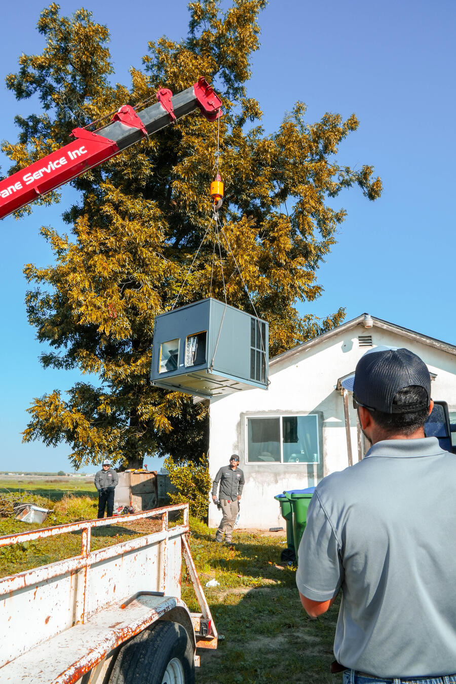 Crane lifting HVAC equipment on an Apex job site