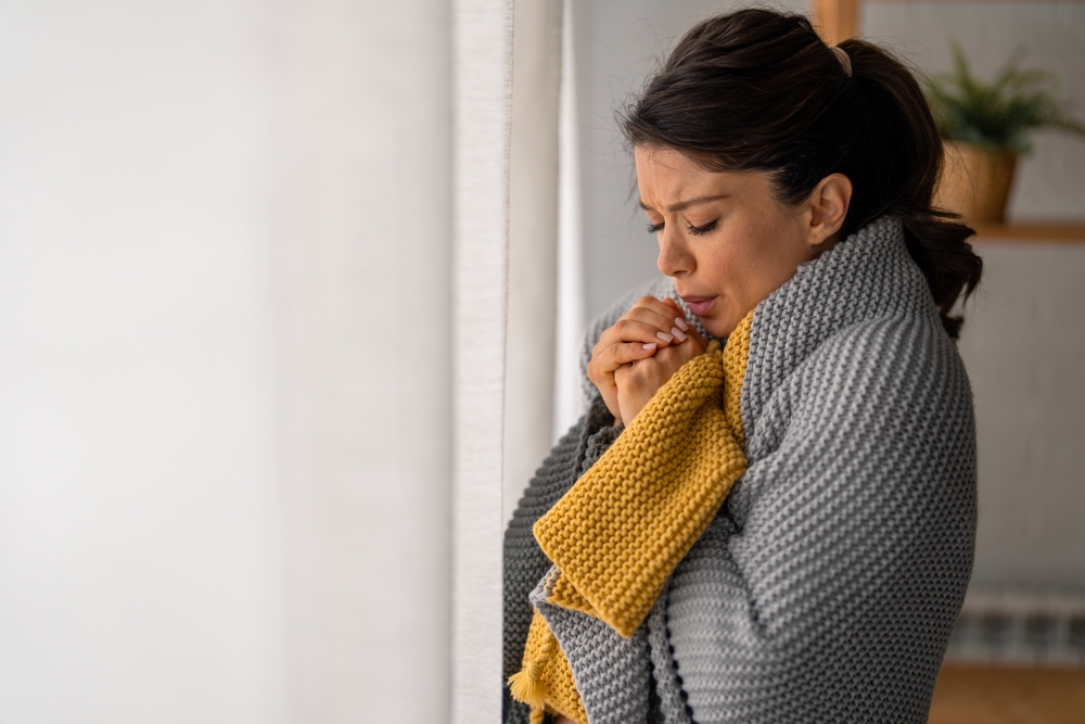 woman breathing on her clasped hands because it's cold in her house